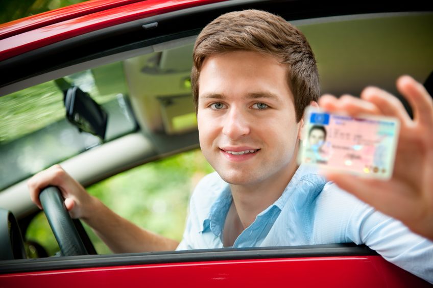 10355206 - teenager sitting in new car and shows his drivers license